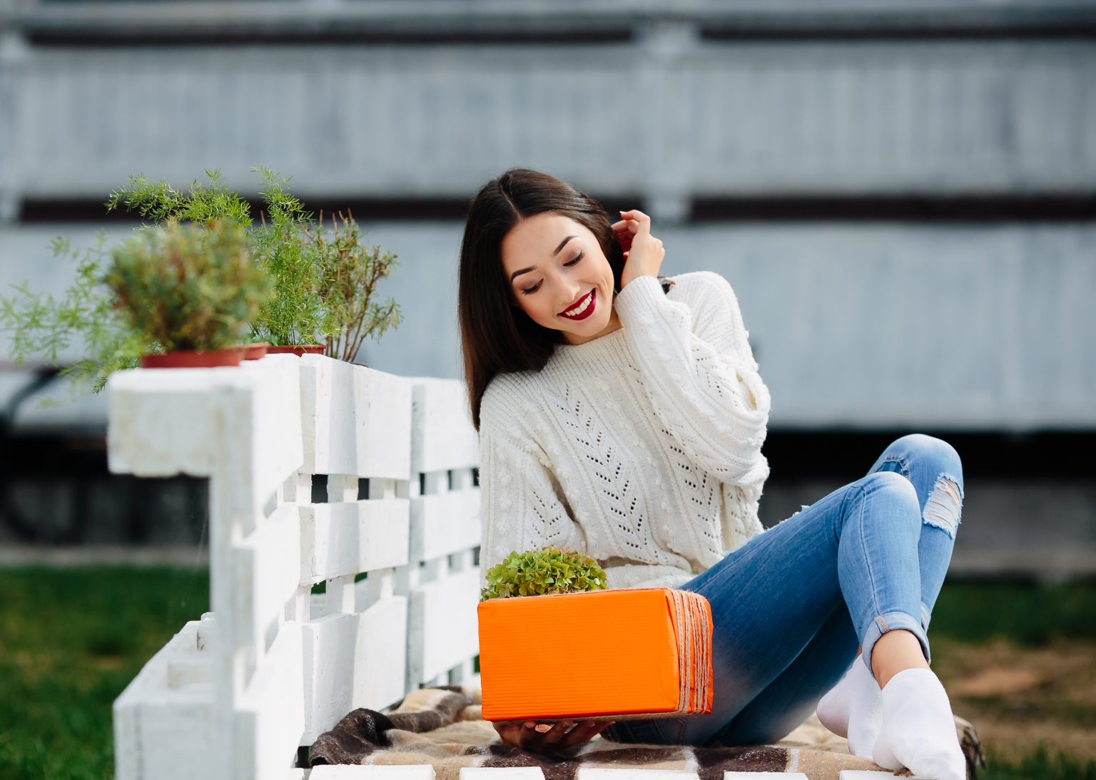 Beautiful girl sitting on a bench and holding in her hands a gift