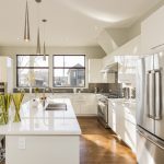 Modern kitchen interior with white cabinets, stainless steel appliances, island bench, and large windows for natural light