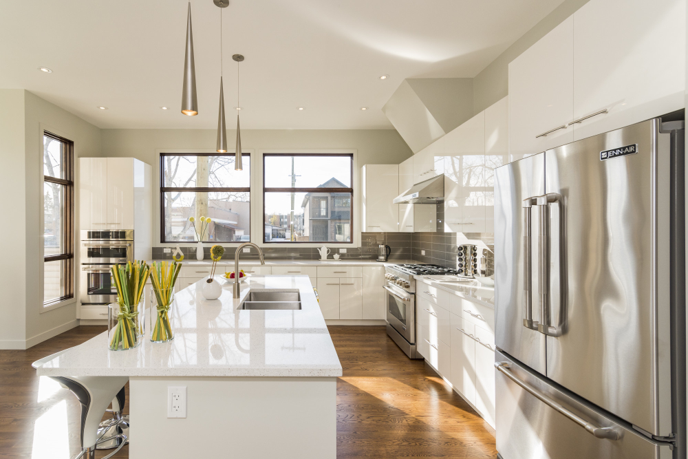 Modern kitchen interior with white cabinets, stainless steel appliances, island bench, and large windows for natural light